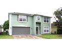Two-story home featuring a gray front door, a two-car garage, solar panels and manicured green lawn at 115 Willowbay Ridge St, Sanford, FL 32771