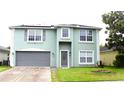 Two-story home featuring a gray front door, a two-car garage, solar panels and manicured green lawn at 115 Willowbay Ridge St, Sanford, FL 32771