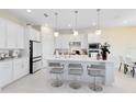 Bright kitchen with white cabinetry, stainless steel appliances, a large island with seating, and modern pendant lighting at 13829 Destin Beach Ln, Orlando, FL 32827