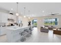 Spacious kitchen and living area featuring a large island with bar stools, modern lighting, and open floor plan at 13829 Destin Beach Ln, Orlando, FL 32827