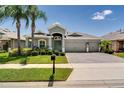Charming single-story home featuring a three-car garage, tropical landscaping, and a paver driveway at 15521 Sandfield Loop, Winter Garden, FL 34787