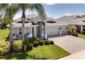 Well-maintained gray house with a three-car garage, manicured lawn, and mature landscaping, including palm trees at 15521 Sandfield Loop, Winter Garden, FL 34787