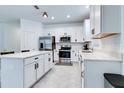 Open kitchen with white cabinets, stainless steel appliances and gray tile flooring at 2043 Rock Maple Bnd, Kissimmee, FL 34746