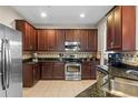 A modern kitchen featuring dark wood cabinets, granite countertops, and stainless-steel appliances at 2122 Bent Grass Ave, Ocoee, FL 34761