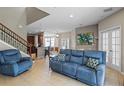 Cozy living room with an open floor plan, tile flooring, staircase, and comfortable blue furniture at 2122 Bent Grass Ave, Ocoee, FL 34761