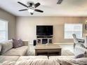 Cozy living room with neutral tones, a comfortable sofa, and a ceiling fan at 1030 Bending Oak Trl, Winter Garden, FL 34787