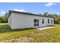 Back of the white home with a sliding glass door and two windows and a small concrete pad at 15684 Sw 37Th Cir, Ocala, FL 34473