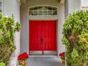 Close-up view of a bright red double front door with manicured landscaping at 1602 Presidio Dr, Clermont, FL 34711