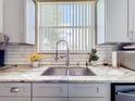Modern Kitchen sink with granite countertop, subway tile backsplash, and grey cabinets at 1602 Presidio Dr, Clermont, FL 34711