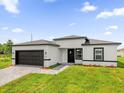 A modern home features a two car garage, gray brick paver driveway, and manicured lawn at 4662 Sw 136Th St, Ocala, FL 34473