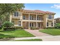 Elegant two-story home showcases a tile roof, covered portico, lush landscaping, and stylish second-story balconies at 8424 Lake Burden Cir, Windermere, FL 34786