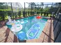Sparkling screened-in pool area surrounded by lush greenery, including inflatables for relaxation and fun at 1929 Nice Ct, Kissimmee, FL 34747