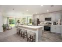 Modern kitchen featuring stainless steel appliances, gray cabinets, a breakfast bar with stools, and open view to the living area at 21 Locust Ter, Ocala, FL 34472
