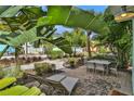 Private outdoor patio area with dining table and lounge chairs surrounded by mature landscaping and tropical foliage at 8061 Lost Shaker Ln, Kissimmee, FL 34747