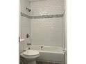Bathroom featuring a white tiled shower with gray accent tiles and modern fixtures at 2075 Dixie Ave, Sanford, FL 32771