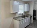 Bright kitchen featuring gray granite countertops and white cabinets complemented by a stainless steel faucet at 2075 Dixie Ave, Sanford, FL 32771