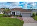 Charming single-story home with manicured lawn, brick driveway, and attached two-car garage at 344 Barbera Dr, Davenport, FL 33897