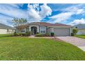 Charming single-story home with manicured lawn, brick driveway, and attached two-car garage at 344 Barbera Dr, Davenport, FL 33897
