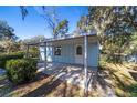 Small light blue house with carport and mature landscaping at 22345 Ne 108Th Avenue Rd, Fort Mc Coy, FL 32134