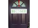 A welcoming front door adorned with a decorative HOME sign and a red ribbon for a touch of charm at 9951 Sw 62Nd Ter, Ocala, FL 34476
