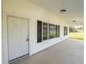 Inviting covered front porch with white siding, black shutters, and concrete flooring at 13026 Ne 6 Pl, Silver Springs, FL 34488