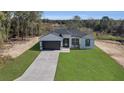 Aerial view of a charming single-story home with a lush green lawn and concrete driveway, surrounded by trees at 35 Locust Terrace Way, Ocala, FL 34472