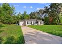 Wide exterior shot of single-story home with long driveway and large lawn at 6 Fisher Way Pl, Ocklawaha, FL 32179