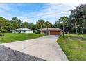 Charming single-story home with a long driveway, mature palm trees, and separate garage at 49 Fisher Way, Ocklawaha, FL 32179