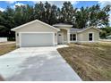 Newly built home with a gray garage door and a small lawn at 1 Pine Trace Trl, Ocala, FL 34472