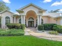 Grand home entrance with classic columns, a double door and a beautifully landscaped front yard at 11831 Sw Highway 484, Dunnellon, FL 34432
