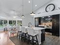 Modern kitchen featuring a center island with seating, dark cabinetry, and a spacious dining area with natural light at 11831 Sw Highway 484, Dunnellon, FL 34432