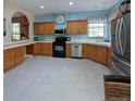 Traditional kitchen featuring wood cabinets, black appliances, light blue walls, and tiled countertops at 4348 Sw Deepwater Ct, Dunnellon, Fl, FL 34431