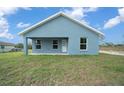 Rear exterior showcasing a covered patio and freshly mowed yard on a house with blue paint and white trim at 14409 Sw 30Th Pl, Ocala, FL 34481