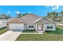 Tan one-story house with white garage door and shutters, and a green lawn at 4414 Sw 170Th Street Rd, Ocala, FL 34473