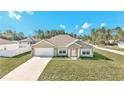 Tan one-story house with white garage door and shutters, and a green lawn at 4414 Sw 170Th Street Rd, Ocala, FL 34473