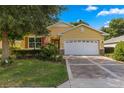 Tan house with white garage door and patterned driveway at 9823 Sw 95Th Loop, Ocala, FL 34481