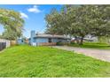 Exterior shot of single story home with brick and blue painted siding and large oak trees in front at 5721 Se 22Nd Pl, Ocala, FL 34480