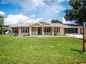 Tan house with red shutters, front porch, and large lawn at 8981 Sw 116Th Place Rd, Ocala, FL 34481