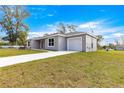 Side view of a gray single story home with a well manicured lawn and a concrete driveway at 4030 Se 134Th St, Belleview, FL 34420