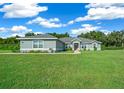 Attractive single-story home featuring a lush green lawn and vibrant landscaping under a bright, sunny sky at 1934 Nw 79Th Loop, Ocala, FL 34475