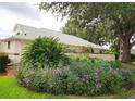 Landscaped yard with mature trees, flowering plants, and blooming purple ground cover at 17808 Se 115Th Ct, Summerfield, FL 34491