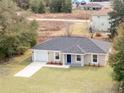 Aerial view of home featuring well-maintained lawn, grey roof, long driveway, and an attached two-car garage at 3694 Sw 149 Ter, Ocala, FL 34481