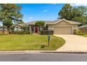 Inviting single-story home with a well-manicured lawn, attached garage, and charming red front door at 2215 Se 24Th Ave, Ocala, FL 34471