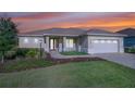 Lovely single-story home with a manicured lawn and a two-car garage during the sunset at 9400 Sw 106Th Ave, Ocala, FL 34481
