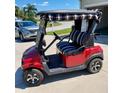 A red Golf Cart with striped seats and canopy parked in front of the home at 12333 Se 177Th Loop, Summerfield, FL 34491