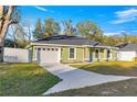 Green house with white garage door and a spacious driveway at 3339 Se 141St Pl, Summerfield, FL 34491