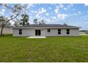 Spacious backyard featuring a gray home with sliding glass doors and a concrete patio at 14573 Sw 25Th Ter, Ocala, FL 34473