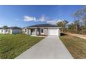 Inviting single-story home with a gray exterior, a long driveway, and a neatly maintained lawn at 15390 Sw 10 Pl, Ocala, FL 34481