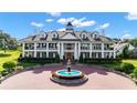 Exterior view of a grand two-story home with a fountain and circular driveway at 22422 Lake Seneca Rd, Eustis, FL 32736