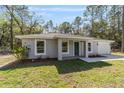 Attractive single-story home with a gray exterior, a well-kept lawn, and tasteful front yard landscaping at 11404 Sw 131St Ter, Dunnellon, FL 34432